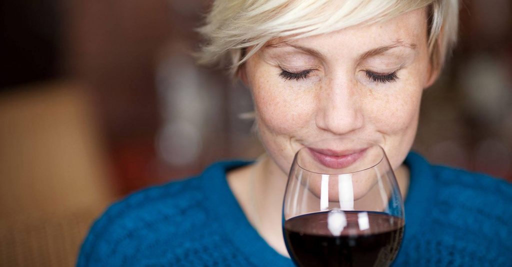 a woman smelling a red wine glass